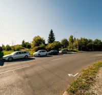 Na predaj stavebný pozemok pre rodinné domy – Banská Bystrica P306ZL - Cesta s parkujúcimi autami a billboardom na Partizánskej ceste, Banská Bystrica, Pozemky - bývanie.