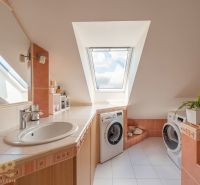 Exkluzívny 3-izbový podkrovný byt s krbom a balkónom - Kúpeľňa v 3-izbovom byte s práčkou, strešným oknom a bielou dlažbou.