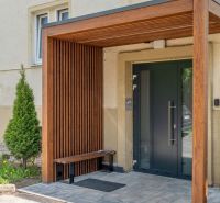Exkluzívny 3-izbový podkrovný byt s krbom a balkónom - Vstup do bytového domu v Poprade s dreveným prístreškom a lavičkou.