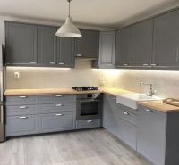 NA PRENÁJOM Pekný 2 izbový byt v Centre Pezinka 700,- EUR - Moderná kuchyňa v 2-izbovom byte so sivými skrinkami a podlahou s dreveným dekorom.