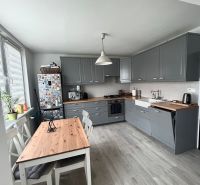 NA PRENÁJOM Pekný 2 izbový byt v Centre Pezinka 700,- EUR - Kuchyňa v 2-izbovom byte s podlahou s dreveným dekorom a šedými skrinkami.