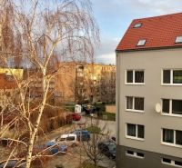 NA PRENÁJOM Pekný 2 izbový byt v Centre Pezinka 700,- EUR - Pohľad na Moyzesovu ulicu v Pezinku s budovami a vetvovým stromom pred 2-izbovým bytom.