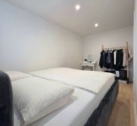 : 1,5-izbový byt, Košice – Juh, loggia, 43 m² - Spálňa v 2-izbovom byte s veľkou posteľou, šatníkom a podlahou s dreveným dekorom.