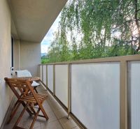 : 1,5-izbový byt, Košice – Juh, loggia, 43 m² - Balkón 2-izbového bytu so skladacími stoličkami a stolom, výhľad na zeleň.
