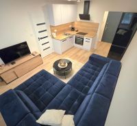 : 1,5-izbový byt, Košice – Juh, loggia, 43 m² - Kuchyňa v 2-izbovom byte s modrým gaučom a podlahou s dreveným dekorom.