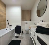 : 1,5-izbový byt, Košice – Juh, loggia, 43 m² - Kúpeľňa v 2-izbovom byte s vaňou, práčkou, zrkadlom a dekoratívnymi prvkami.
