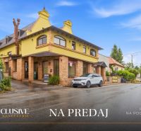 Na predaj zabehnutá reštaurácia s klientelou, Nitra - Ulica s budovou Gastro priestory na predaj v Nitre, lemovaná zeleňou a parkoviskom.