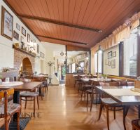 Na predaj zabehnutá reštaurácia s klientelou, Nitra - Gastro priestory s podlahou s dreveným dekorom, stolmi a dekoráciami na stenách.