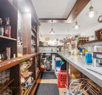Na predaj zabehnutá reštaurácia s klientelou, Nitra - Interiér gastro priestorov s barom a nápojmi na poličkách, podlaha s dreveným dekorom.
