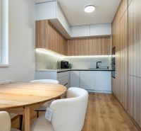 3-izb.byt | Novostavba | Popradská, Košice | 72,75 m² + loggia - Kuchyňa so stolom v 3-izbovom byte, podlaha s dreveným dekorom a zabudované spotrebiče.