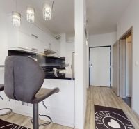 | Zariadený 1,5 izbový byt | 35m² | SLNEČNICE - Kuchyňa v 2-izbovom byte s barovými stoličkami a zrkadlom na stene.