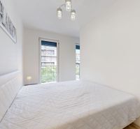 | Zariadený 1,5 izbový byt | 35m² | SLNEČNICE - Spálňa v 2-izbovom byte s pohodlnou posteľou a výhľadom na budovy.