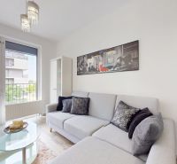 | Zariadený 1,5 izbový byt | 35m² | SLNEČNICE - Obývačka v 2-izbovom byte s pohodlnou sedačkou, obrazom na stene a veľkými oknami.