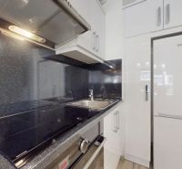 | Zariadený 1,5 izbový byt | 35m² | SLNEČNICE - Kuchyňa v 2-izbovom byte so vstavanými spotrebičmi, nerezovým drezom a lesklými skrinkami.