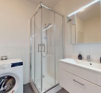 | Zariadený 1,5 izbový byt | 35m² | SLNEČNICE - Kúpeľňa v 2-izbovom byte s práčkou, sprchovým kútom a umývadlom s úložným priestorom.
