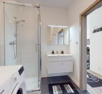 | Zariadený 1,5 izbový byt | 35m² | SLNEČNICE - Kúpeľňa v 2-izbovom byte, s práčkou, sprchovým kútom a umývadlom s osvetleným zrkadlom.