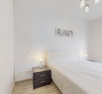 | Zariadený 1,5 izbový byt | 35m² | SLNEČNICE - Svetlá spálňa v 2-izbovom byte s posteľou, nočným stolíkom a balkónom.