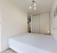 | Zariadený 1,5 izbový byt | 35m² | SLNEČNICE - Spálňa v 2-izbovom byte s bielou posteľou, vstavanou skriňou a dekoratívnymi prvkami.