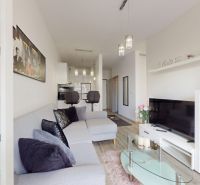 | Zariadený 1,5 izbový byt | 35m² | SLNEČNICE - Obývacia izba v 2-izbovom byte s pohodlnou sedačkou a vešiakom na stene.