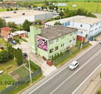 Na predaj veľkom. 3-izb. byt so záhradou, Veľký Meder - Ulica s budovami vo Veľkom Mederi, za ktorými sa rozprestiera zelená krajina.