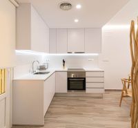 Predaj- Apartmány - La Manga del Mar Menor- Španielsko  - Kuchyňa v rekreačnom apartmáne s bielymi skrinkami a podlahou s dreveným dekorom.