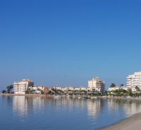 Predaj- Apartmány - La Manga del Mar Menor- Španielsko  - Pobrežie s rekreačnými apartmánmi v La Manga del Mar Menor pri pokojnom mori a modrej oblohe.