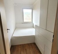 Prenájom 3 izbový byt, Teplická ulica, Bratislava III. Nové Mesto - Úzka izba s posteľou a vstavanými skriňami, podlaha s dreveným dekorom.