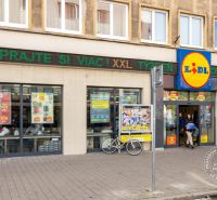 2 izb.byt, TEHLA, PARKING, BA I. St. Mesto, Grösslingova - Lidl na Grösslingovej ulici v Bratislave - Staré Mesto s okoloidúcimi ľuďmi a bicyklom.