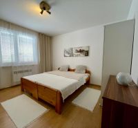 PREDAJ - 3 izbový rodinný dom Trnovec nad Váhom - Spálňa s posteľou, bielymi závesmi a podlahou s dreveným dekorom v rodinnom dome.