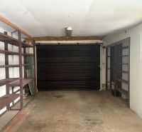 PREDAJ - Rodinný dom s investičným potenciálom - Nové Zámky - Garáž v rodinnom dome s policami a rolovacími dverami.