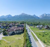 NA PREDAJ: Zabehnutý hotel Amália s wellnesom v srdci Vysokých Tatier - Pohľad na Hotely a penzióny v Novej Lesnej s Vysokými Tatrami v pozadí.