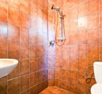 PREDAJ - Rodinný dom - Pavlice, Celková rozloha 1469m² - Kúpeľňa s oranžovými obkladmi, umývadlom, toaletou a sprchou v rodinnom dome.