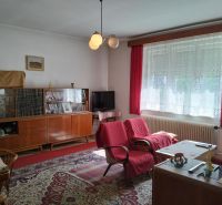 Rodinný dom, Sučany - Obývačka v rodinnom dome s červenými kreslami a sklennou vitrínou, podlaha s dreveným dekorom.