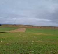 Stavebný pozemok 2 335 m² v obci Valča  - Zeleň s vežou a stĺpmi v diaľke, Valča, Pozemky - bývanie.