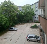 Priestranná garzónka s balkónom v novostavbe. - Parkovisko na Športovej ulici v Dunajskej Lužnej s autami a zeleňou v pozadí.