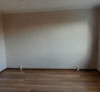 Pekný 2 izbový byt s balkónom na prenájom. - Izba v 2-izbovom byte s podlahou s dreveným dekorom a veľkým oknom.