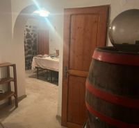 PREDAJ/ Krásna chalupa s vinicou/Jablonov nad Turňou - Sklep chaty s dreveným sudom a kamennou stenou, vidieť stôl v pozadí.