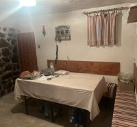 PREDAJ/ Krásna chalupa s vinicou/Jablonov nad Turňou - Jedálenský kút s obrusom, lavicou a kameňom na stene v chate.