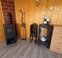 REZERVOVANÁ / Záh. chata s altánkom, pozemok 534m2, ZO Kunov I, Senica - Drevený interiér chaty s pecou, žirafou a nábytkom na podlahe s dreveným dekorom.