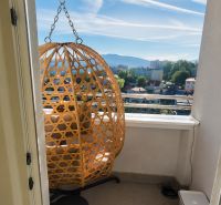 Prenájom: moderný 2-izbový byt s balkónom, Čadca SNP - Balkón v 2-izbovom byte s ratanovým kreslom a výhľadom na mesto.