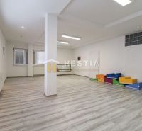 Komerčný priestor v centre mesta - Priestranné obchodné priestory s podlahou s dreveným dekorom a farebnými sedacími prvkami.