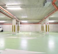 UZBECKÁ, parkovacie miesto v garáži, novostavba Oppidum - Podzemné garáže s parkovacím miestom, zelenou podlahou a oranžovým potrubím.