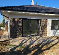 Bungalov v centre obce Cabaj v štandarde, Wágnerova ulica, Dom č.2 - Rodinný dom v Cabaj-Čápore s tehlovou fasádou, posuvnými dverami a dlažbou na terase.