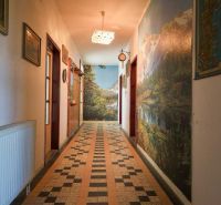 PREDAJ - Rodinný dom s priestranným pozemkom 2266 m² - Veľký Kýr - Chodba v rodinnom dome s dlažbou, obrazmi a svetlom na strope.