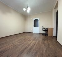 Na predaj: CENTRUM 3 izb.byt + LOGGIA + KLÍMA + PIVNICA - Izba v 3-izbovom byte s podlahou s dreveným dekorom, študentským stolom a stoličkou.