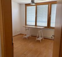 4 izbový byt 120 m2 Ružová dolina, Ružinov, 1x podzemné´parkovanie - Miestnosť s veľkým oknom, stolom a podlahou s dreveným dekorom v 4-izbovom byte.