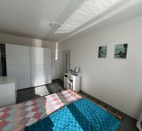 Na prenájom pekný, zariadený 2. izbový byt, sídlisko 2., Prešov - Spálňa v 2-izbovom byte s posteľou, bielou skriňou a podlahou s dreveným dekorom.