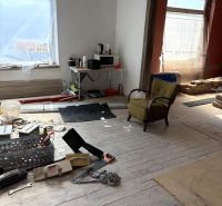 INVESTIČNÁ PRÍLEŽITOSŤ– centrum mesta | podnikanie, bývanie - Interiér s rozloženými nástrojmi, kreslom a stolom v rodinnom dome s drevenou podlahou.