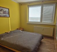 Prenájom 2 izbový byt Poprad - loggia - Spálňa v 2-izbovom byte so žltými stenami, skriňou a podlahou s dreveným dekorom.