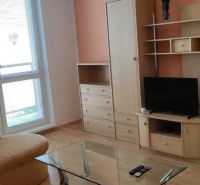 Prenájom 2 izbový byt Poprad - loggia - Obývacia izba v 2-izbovom byte s nábytkom a televízorom, podlaha s dreveným dekorom.